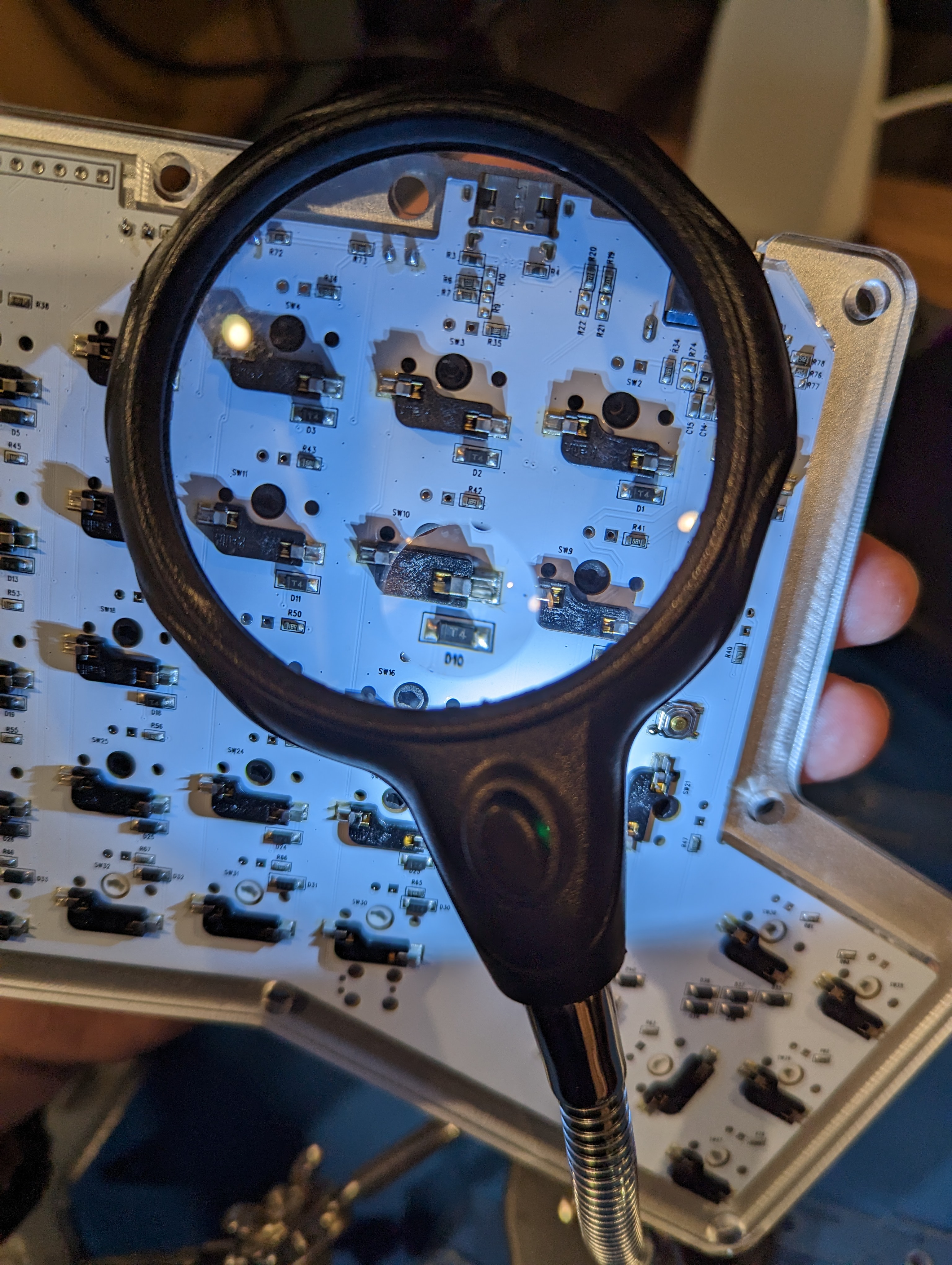 examining back of circuit board with a magnifying lens