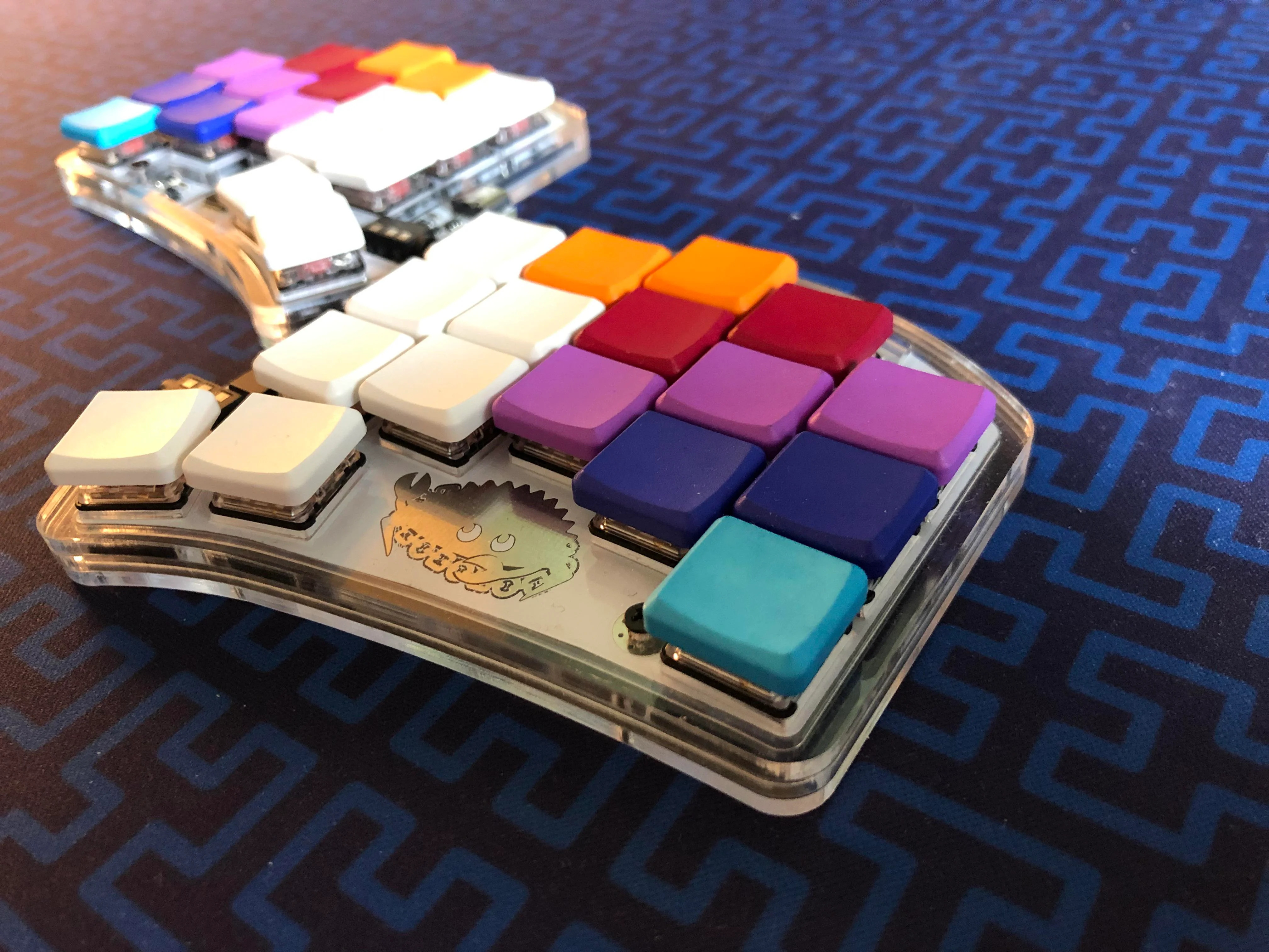 a stylishly angled picture of a tiny split-style keyboard with multicolored blank keycaps